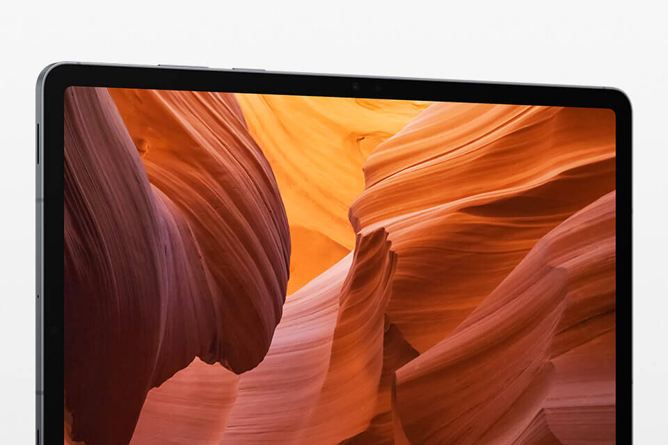 Ekran Galaxy Tab S11 wyświetla żywy, kolorowy obraz, podkreślając wciągającą jakość wyświetlacza tabletu dzięki cieńszej ramce. Na obrazie widoczny jest fragment ekranu tabletu z wyświetlanym krajobrazem skalnym w odcieniach pomarańczowych i brązowych. Ramka urządzenia jest cienka i ciemna.