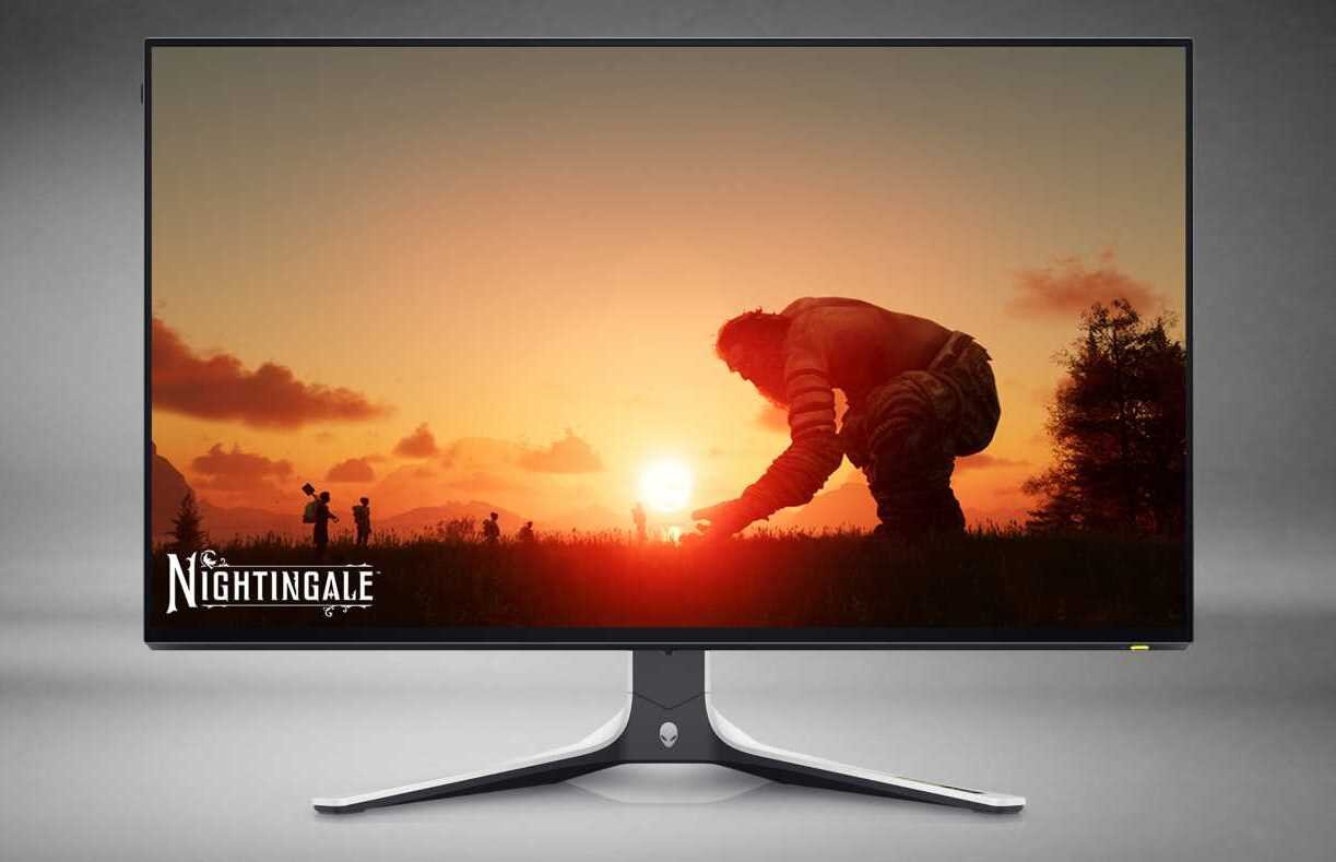Monitor wyświetla obraz z gry, przedstawiający postać klęczącą na tle zachodzącego słońca. W lewym dolnym rogu ekranu widnieje napis \'Nightingale\'.