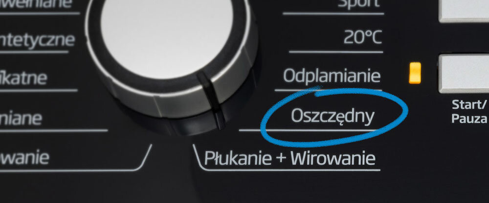 Panel sterowania pralki z pokrętłem i przyciskami. Widoczny tekst: \'Oszczędny\', \'Odplamianie\', \'Płukanie + Wirowanie\'.