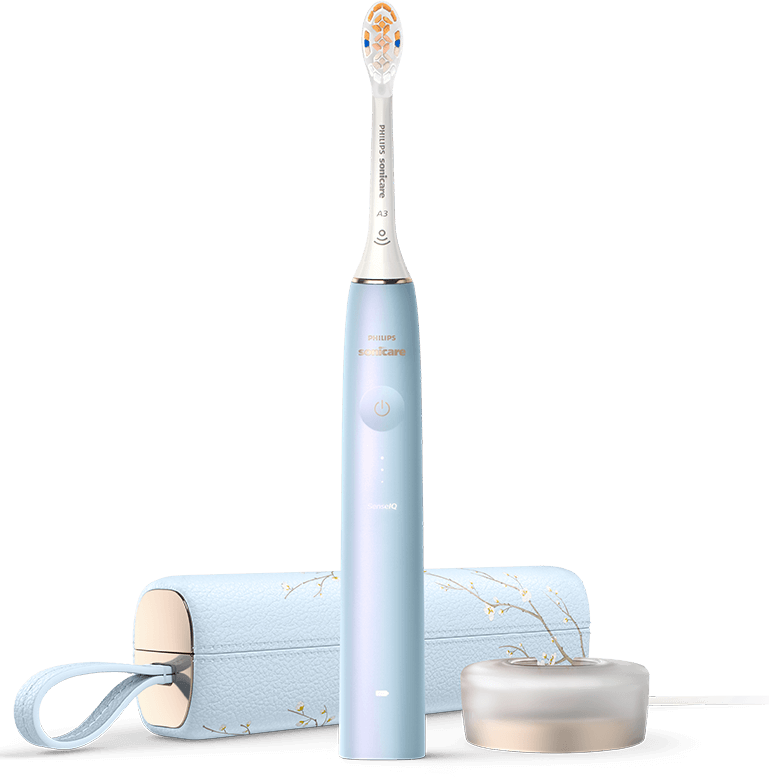 Szczoteczka soniczna w kolorze niebieskim z napisem \'PHILIPS Sonicare\' na rączce, obok znajduje się etui i ładowarka. Na szczoteczce widoczny jest przycisk zasilania oraz wskaźniki LED.