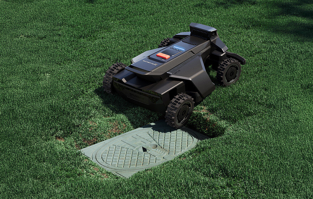 Robot koszący na trawie, obok znajduje się prostokątna pokrywa. Na robocie widoczne jest logo \'Segway\'.
