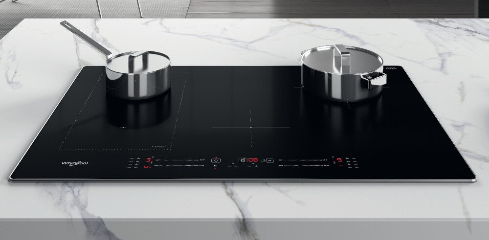 Czarna płyta indukcyjna z dwoma garnkami na marmurowym blacie. Widoczne logo Whirlpool oraz panel dotykowy z czerwonymi i białymi oznaczeniami.