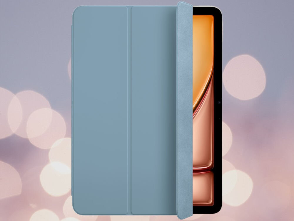 Na obrazie widoczne jest niebieskie etui na tablet, częściowo zakrywające ekran urządzenia. Tło jest rozmyte z jasnymi, okrągłymi światłami.