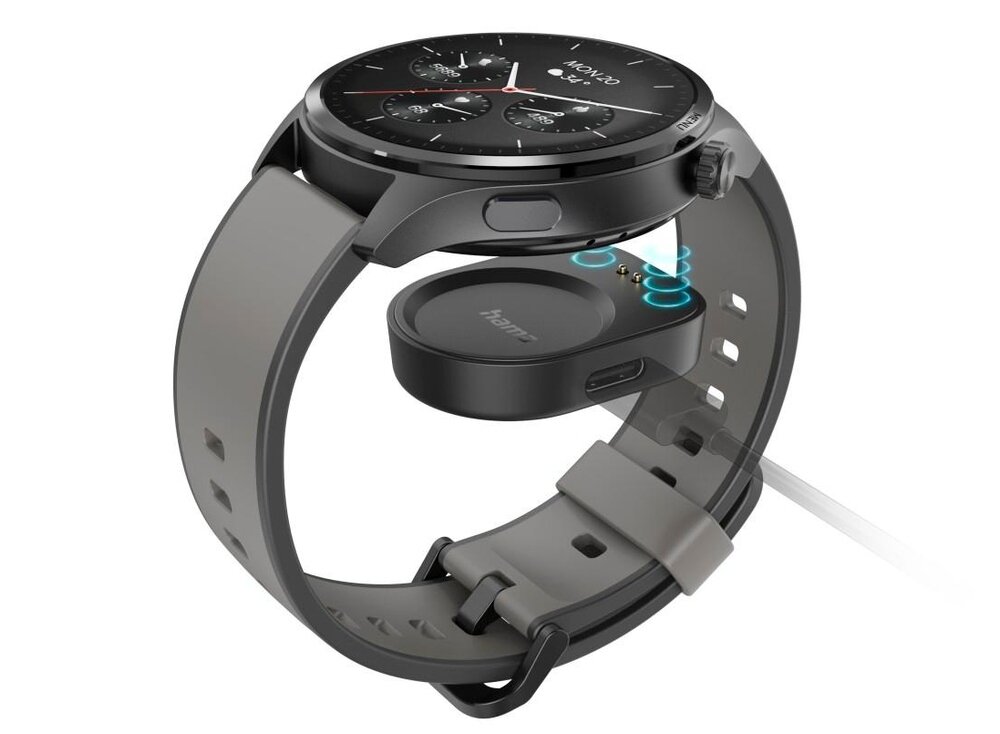 Smartwatch z okrągłą tarczą i czarno-szarym paskiem, obok którego znajduje się ładowarka z logo \'hama\'.