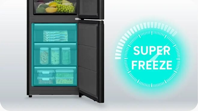 Obraz przedstawia otwartą czarną lodówkę z widocznymi półkami wypełnionymi jedzeniem. Obok lodówki znajduje się niebieski napis \'SUPER FREEZE\'.