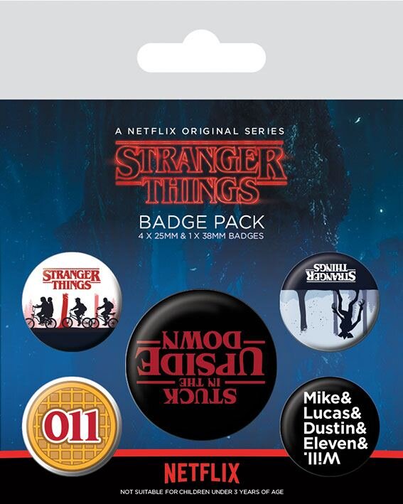 Opakowanie zawiera pięć przypinek z motywami z serialu \'Stranger Things\', w tym napisy \'STUCK IN THE UPSIDE DOWN\' i \'011\'. Na dole widnieje logo \'NETFLIX\' oraz informacja \'NOT SUITABLE FOR CHILDREN UNDER 3 YEARS OF AGE\'.
