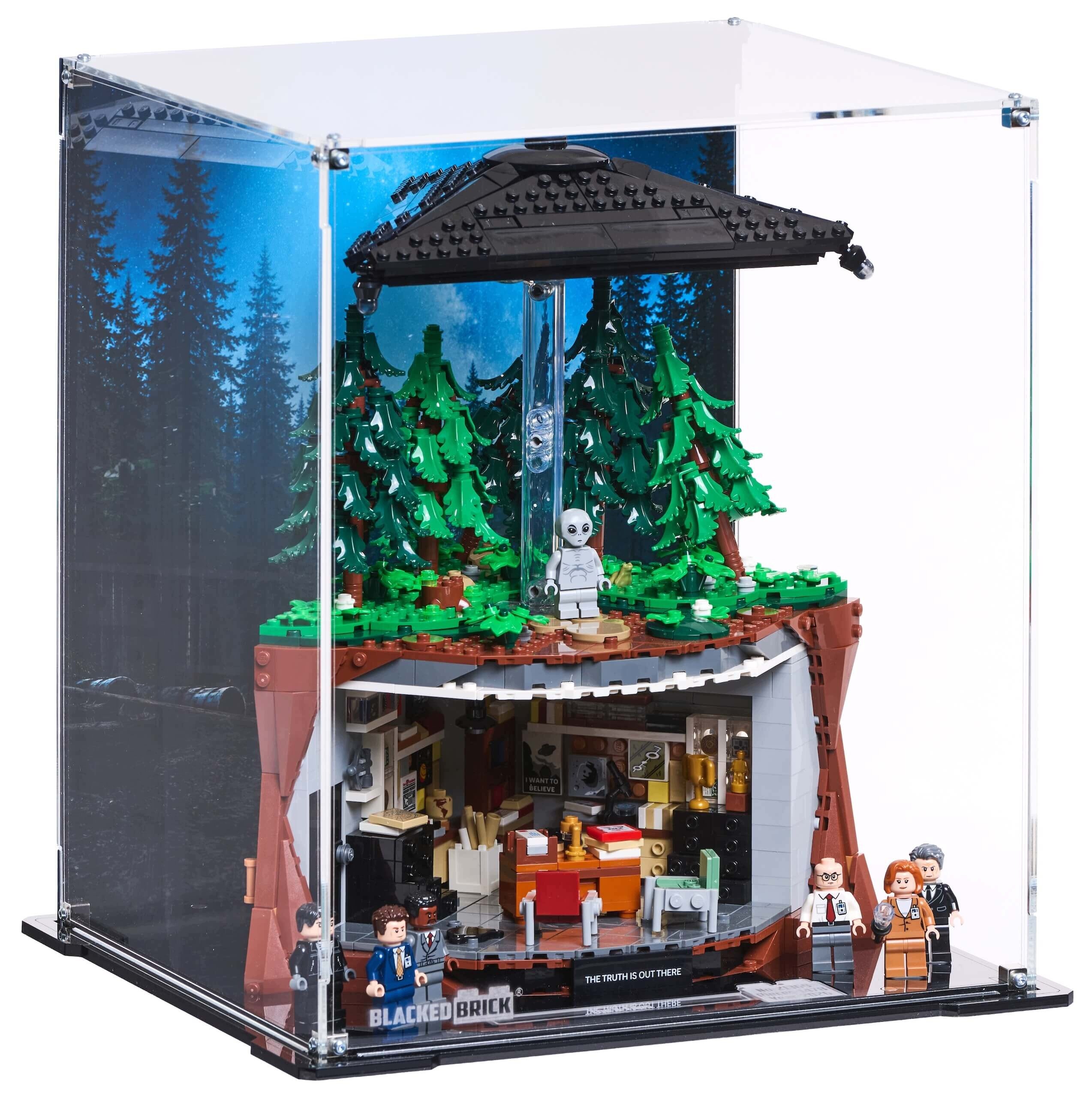 Gablota z przezroczystymi ścianami zawiera scenę z klocków LEGO przedstawiającą las z drzewami, figurką kosmity i wnętrzem biura. Na podstawie widnieje napis \'BLACKED BRICK\' oraz \'THE TRUTH IS OUT THERE\'.