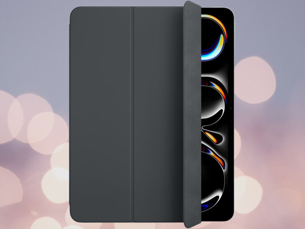 Czarne etui na tablet z widocznym fragmentem ekranu urządzenia, na którym widać kolorowe wzory. Tło jest rozmyte z jasnymi, okrągłymi światłami.