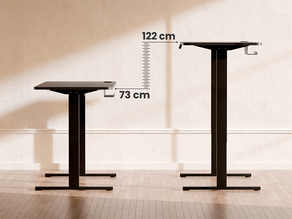 Na obrazie widoczne są dwa biurka o regulowanej wysokości, jedno ustawione na 73 cm, a drugie na 122 cm. Tło stanowi jasna ściana i drewniana podłoga.