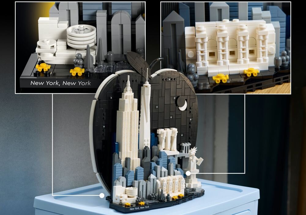 Model LEGO przedstawiający panoramę Nowego Jorku z charakterystycznymi budynkami, umieszczony na podstawce w kształcie jabłka. Widoczny jest napis \'New York, New York\'.
