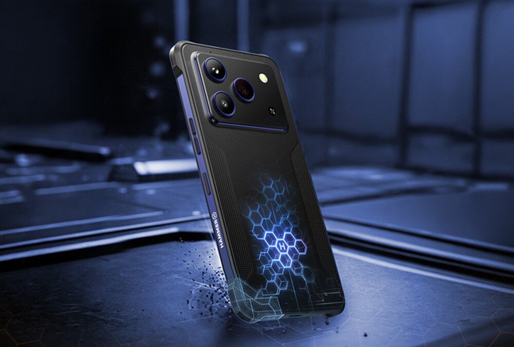 Smartfon HAMMER Blade 6 Pro 5G Smartfon w pancernej obudowie stojący na metalowym podłożu z widocznym tyłem, wyspą aparatów oraz świecącym wzorem plastra miodu