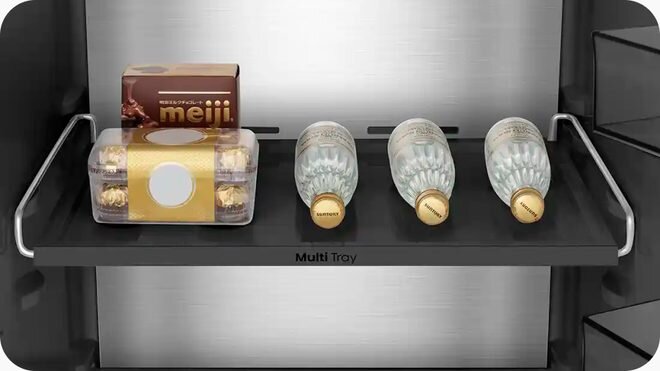 Półka lodówki z napisem \'Multi Tray\' zawiera pudełko czekoladek \'meiji\', opakowanie pralinek oraz trzy butelki wody mineralnej \'San Benedetto\'.