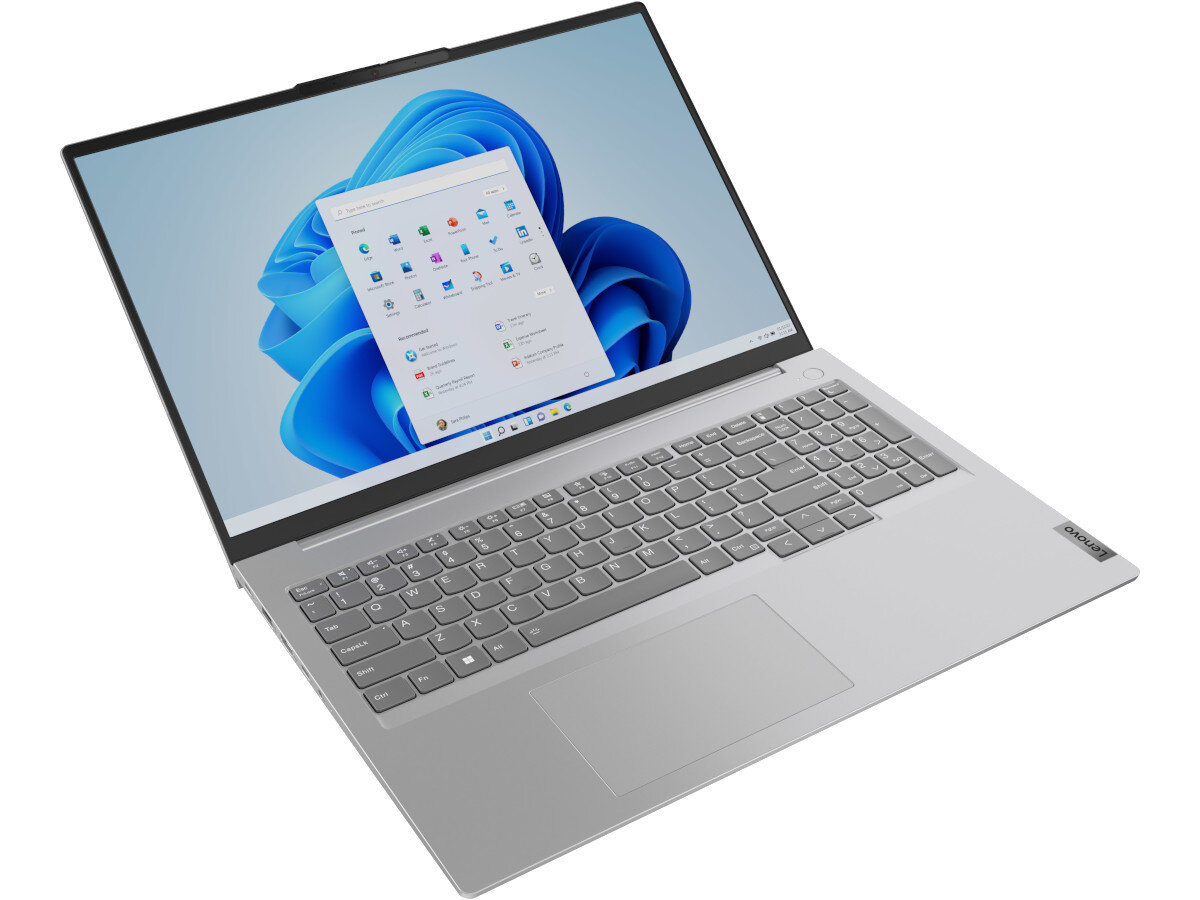 Na obrazie widoczny jest srebrny laptop z otwartym ekranem, na którym wyświetlany jest pulpit systemu Windows 11. Na obudowie laptopa znajduje się logo \'Lenovo\'.