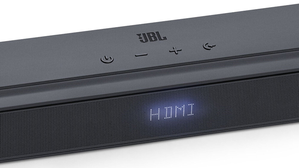 Czarny soundbar z widocznym logo \'JBL\' na górnej części oraz wyświetlaczem pokazującym tekst \'HDMI\'. Na górze znajdują się przyciski z symbolami zasilania, zmniejszania i zwiększania głośności oraz Bluetooth.