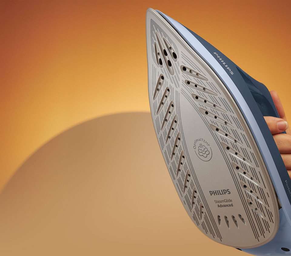 Zdjęcie przedstawia stopę żelazka z widocznymi otworami parowymi i napisami: \'Optimal TEMP\', \'PHILIPS\', \'SteamGlide Advanced\'.