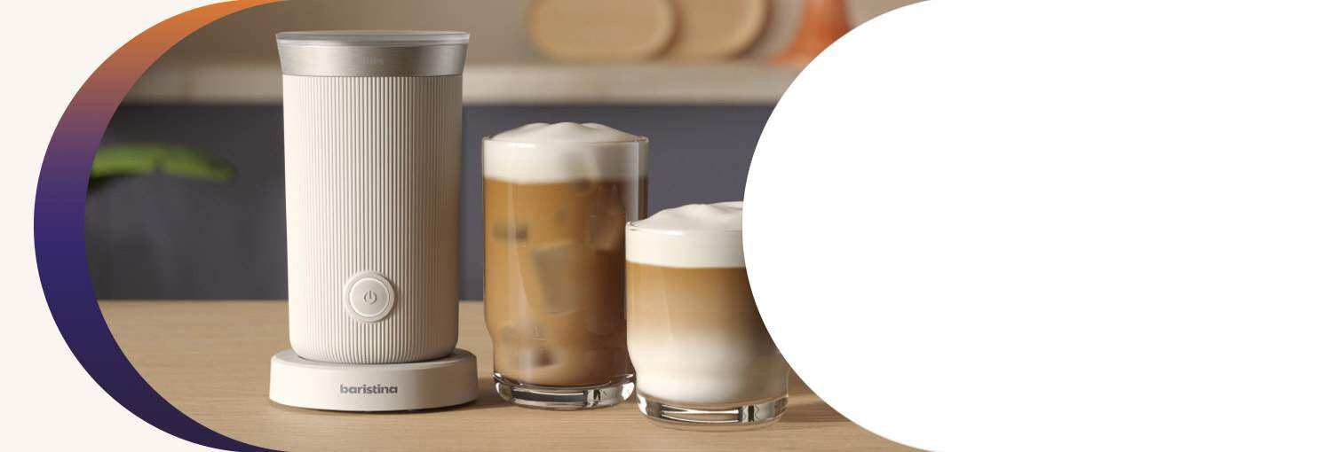 Na drewnianym blacie stoi biały spieniacz do mleka z napisem \'baristina\', obok znajdują się dwa szklane kubki z kawą i pianką mleczną.