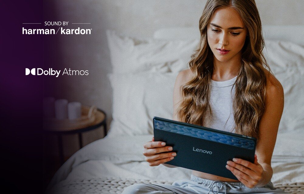 Osoba trzyma tablet z widocznym logo Lenovo. Na obrazie znajdują się napisy: \'SOUND BY harman/kardon\' oraz \'Dolby Atmos\'.