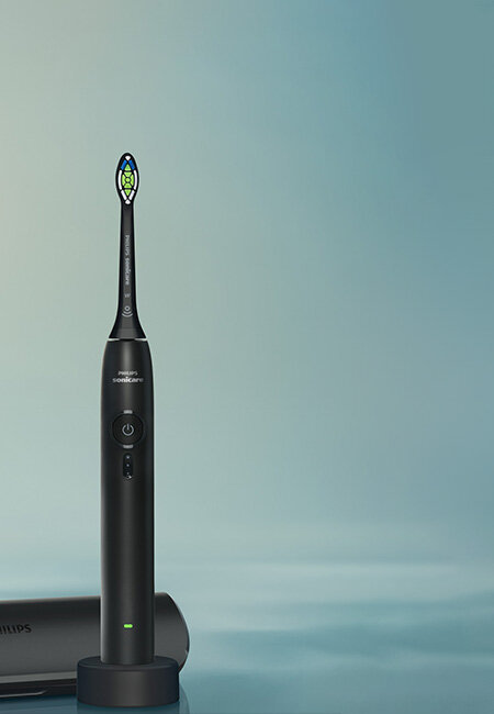 Czarna szczoteczka soniczna z widocznym logo \'Philips Sonicare\' na tle w odcieniach niebieskiego. Obok znajduje się etui z napisem \'Philips\'.