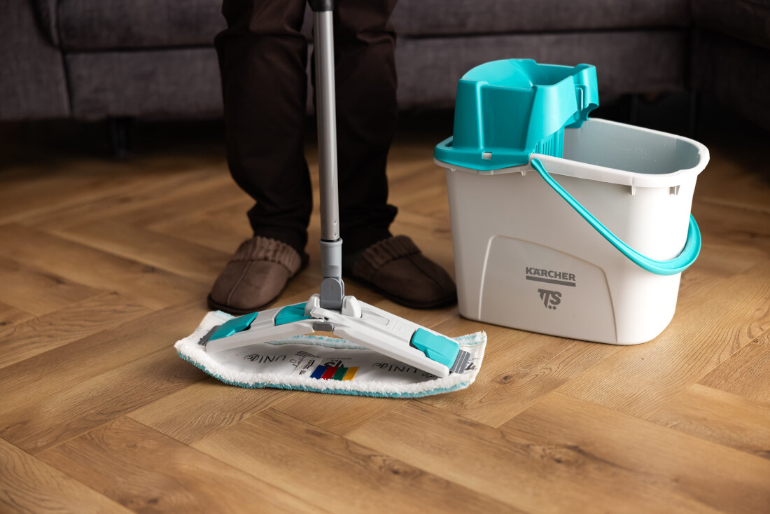 Osoba używa mopa płaskiego obok białego wiadra z turkusowym uchwytem i logo \'KARCHER TTS\'.