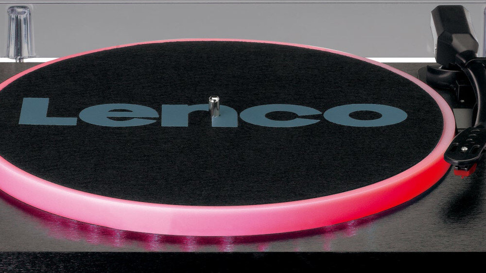 Gramofon z widocznym logo \'Lenco\' na czarnej powierzchni talerza, otoczony różowym podświetleniem LED.