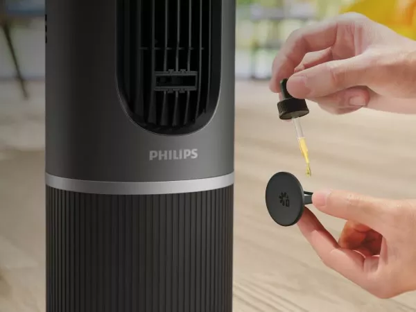 Ciemnoszary wentylator z widocznym logo PHILIPS, obok którego ręka trzyma pipetę z żółtym płynem i okrągły element z symbolem kwiatka.