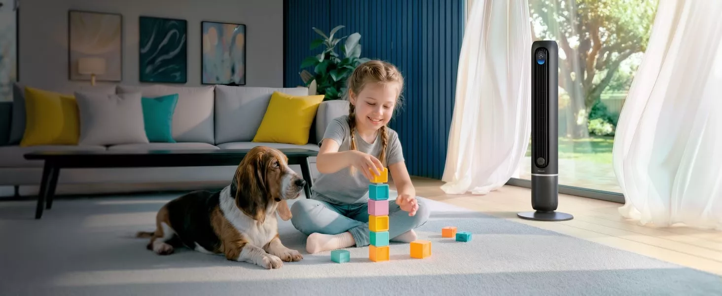 Dziewczynka bawi się kolorowymi klockami na dywanie, obok niej leży pies. W tle stoi ciemnoszary wentylator z widocznym logo PHILIPS.