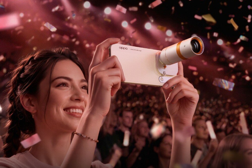 Smartfon OPPO Find X10 Pro Max Uśmiechnięta kobieta na koncercie trzyma w dłoniach smartfon z doczepionym obiektywem w otoczeniu opadającego konfetti