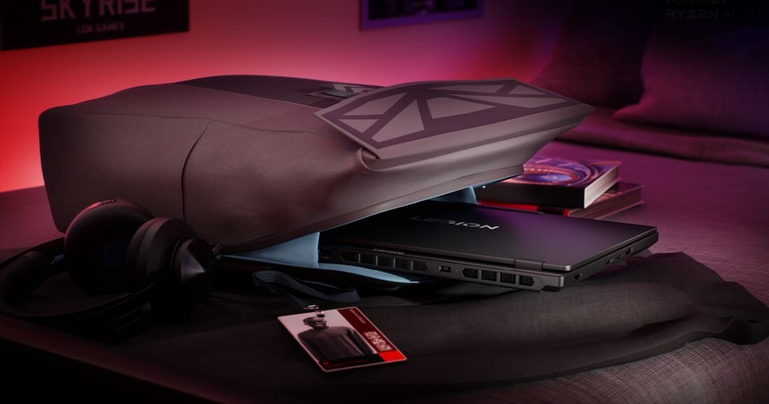 Na obrazie widać czarny laptop z napisem \'LEGION\' na obudowie, częściowo wysunięty z torby. Obok znajdują się słuchawki i karta z napisem \'SKYRISE\'.