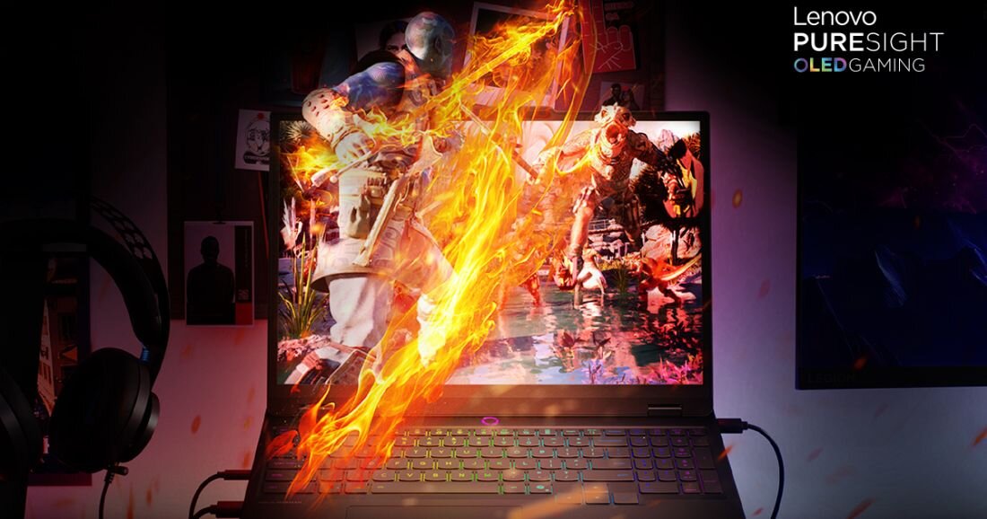 Na obrazie widoczny jest laptop z wyświetlaczem, na którym przedstawiona jest dynamiczna scena z gry z efektem płomieni. W prawym górnym rogu znajduje się tekst: \'Lenovo PURESIGHT OLED GAMING\'.