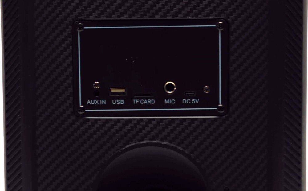 Panel z gniazdami na urządzeniu audio, zawierający wejścia AUX IN, USB, TF CARD, MIC oraz DC 5V. Obudowa ma wzór przypominający włókno węglowe.