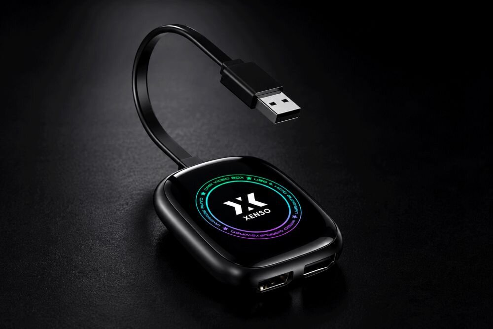 Czarny adapter z logo XENSO, posiadający port USB i krótki kabel zakończony wtykiem USB. Na powierzchni widoczny jest kolorowy okrąg z napisem XENSO.