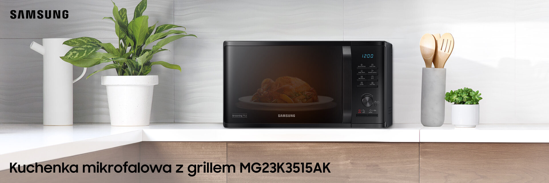 Na blacie kuchennym stoi czarna kuchenka mikrofalowa z grillem marki Samsung, obok której znajduje się biały dzbanek z rośliną oraz pojemnik z drewnianymi przyborami kuchennymi. Na drzwiczkach kuchenki widoczny jest napis \'Samsung\', a na obrazie znajduje się tekst: \'Kuchenka mikrofalowa z grillem MG23K3515AK\'.