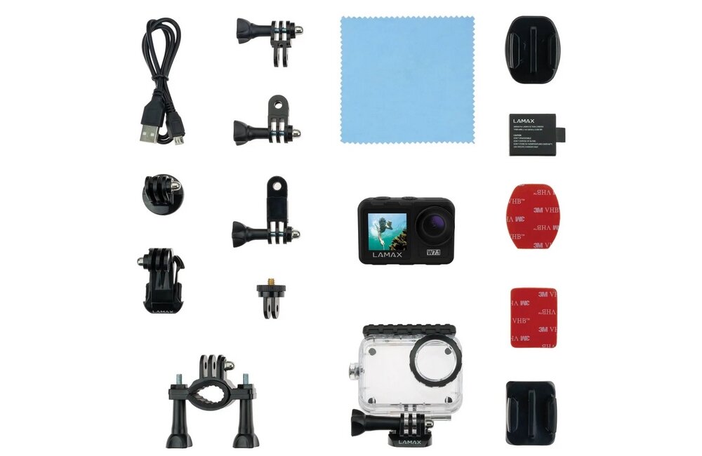 Na obrazie znajduje się zestaw akcesoriów do kamery sportowej, w tym kamera LAMAX, różne uchwyty, kabel USB, bateria, przezroczysta obudowa ochronna oraz ściereczka z mikrofibry. Widoczne są również elementy montażowe z logo \'3M\' i \'LAMAX\'.