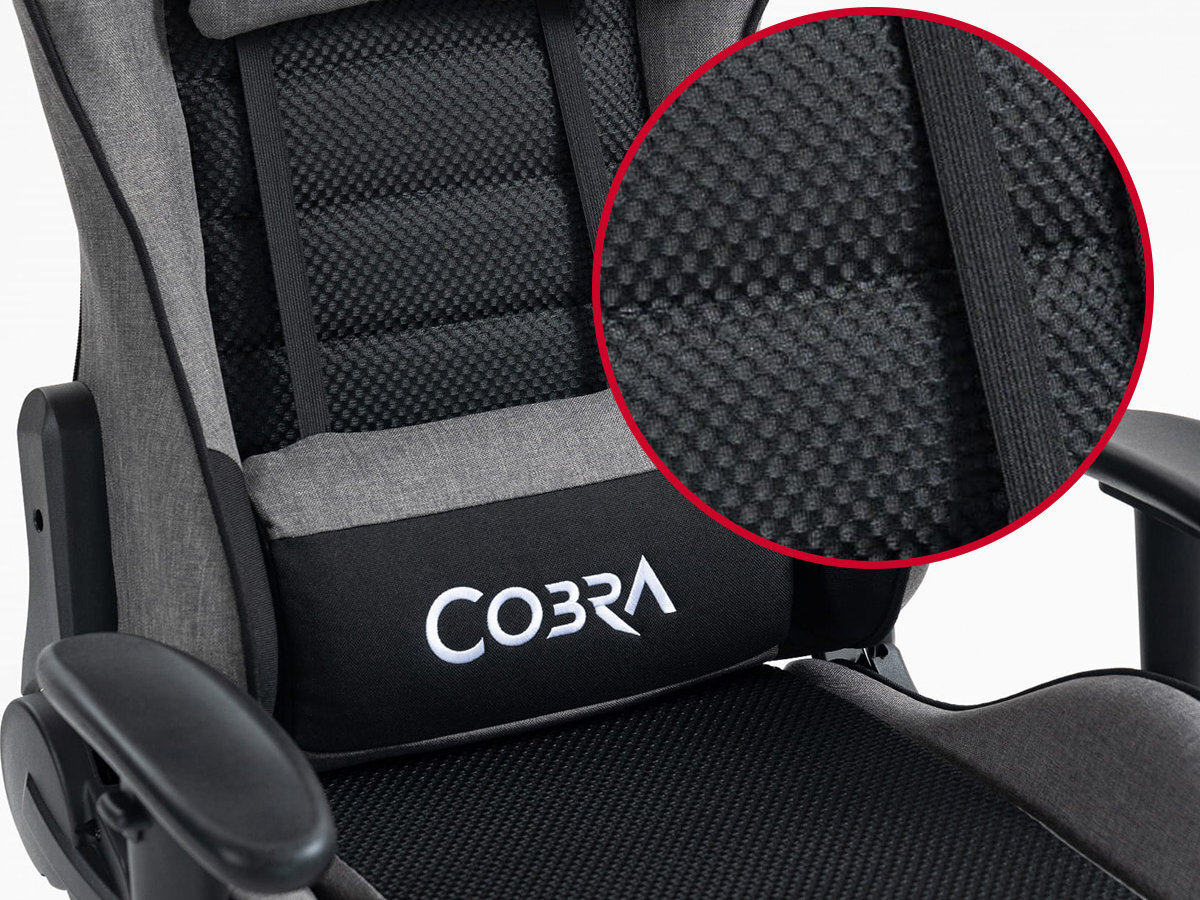 Fotel gamingowy w kolorze szaro-czarnym z widocznym logo \'COBRA\' na poduszce lędźwiowej. Zbliżenie pokazuje teksturę materiału o strukturze siatki.