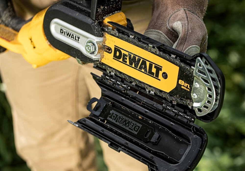 Osoba trzyma piłę łańcuchową z widocznym logo \'DEWALT\' na żółtej obudowie. Na piłę nałożona jest osłona z napisem \'DEWALT\'.