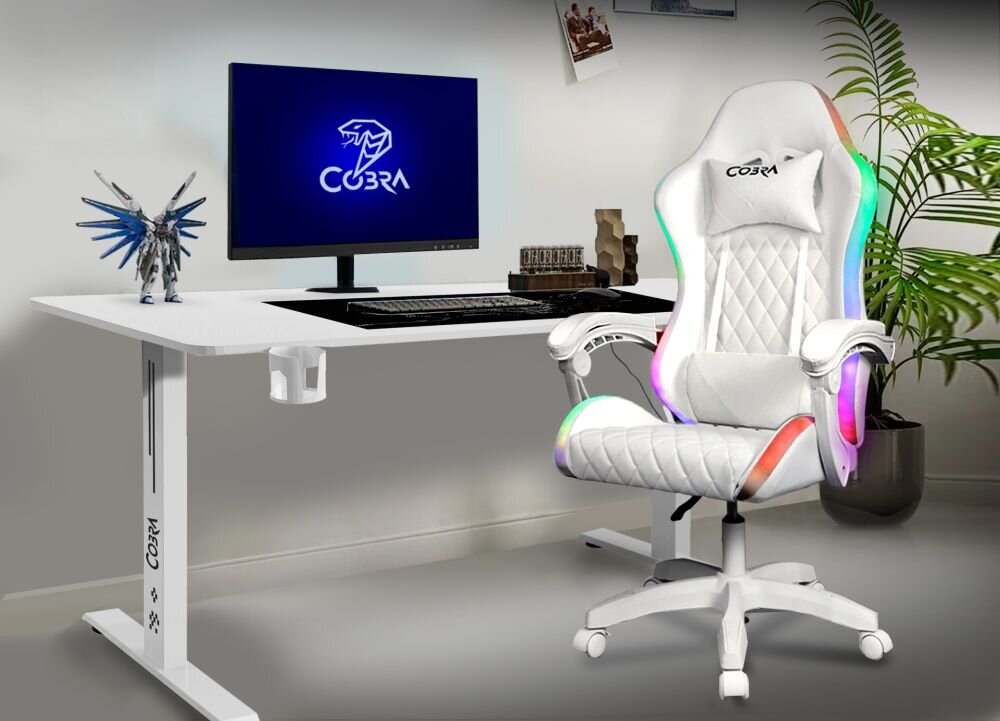 Na obrazie znajduje się białe biurko gamingowe z logo \'COBRA\' oraz biały fotel gamingowy z kolorowymi podświetleniami. Na biurku stoi monitor z logo \'COBRA\', klawiatura, myszka i figurka smoka.