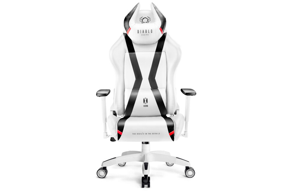 Biało-czarny fotel gamingowy z logo \'DIABLO CHAIRS\' na zagłówku i napisem \'THE DEVIL IS IN THE DETAILS\' na siedzisku. Fotel posiada podłokietniki i kółka, a jego design jest nowoczesny z wyraźnymi czarnymi pasami.