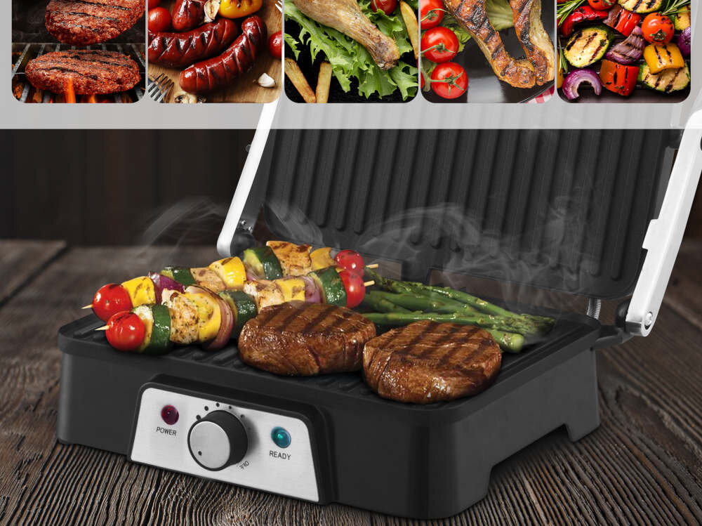 Grill elektryczny z otwartą pokrywą, na którym znajdują się grillowane mięso, szaszłyki i szparagi. Na panelu sterowania widoczne są przyciski \'POWER\' i \'READY\'.