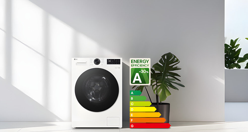 Na obrazie znajduje się biała pralka z czarnym bębnem, obok której stoi znak efektywności energetycznej z klasą A i napisem \'ENERGY EFFICIENCY -30%\'. W tle widoczna jest roślina doniczkowa na jasnym tle.
