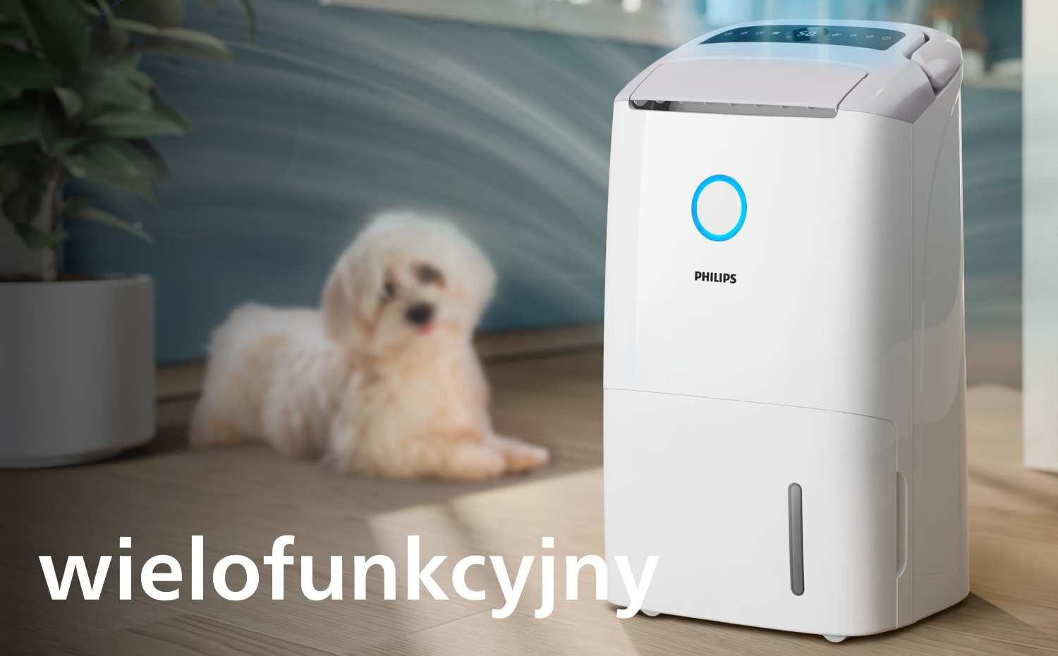 Na obrazie znajduje się biały osuszacz powietrza z logo PHILIPS i niebieskim okręgiem na przednim panelu. W tle widoczny jest pies, a na dole napis \'wielofunkcyjny\'.