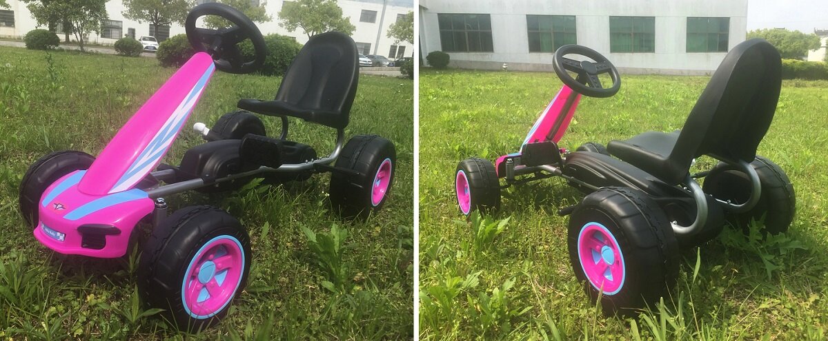 Na trawie stoi różowy gokart na pedały z czarnym siedzeniem i kierownicą. Koła gokarta mają różowe felgi.