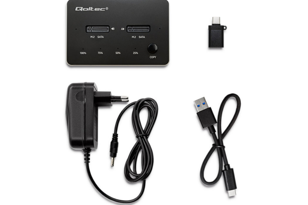 Na obrazie znajduje się stacja dokująca z logo \'Qoltec\', dwa gniazda M.2 SATA, przycisk \'COPY\' oraz wskaźniki procentowe. Obok widoczne są zasilacz, kabel USB oraz adapter USB Typu C.