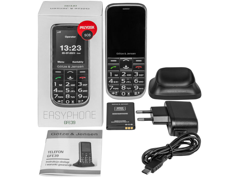 Na obrazie znajduje się telefon Götze & Jensen GFE39 z dużymi przyciskami, obok niego pudełko, ładowarka, bateria, stacja dokująca oraz instrukcja obsługi. Na ekranie telefonu widoczny jest czas 13:23 i data 20-07-2023, a na pudełku napis \'PRZYCISK SOS\'.
