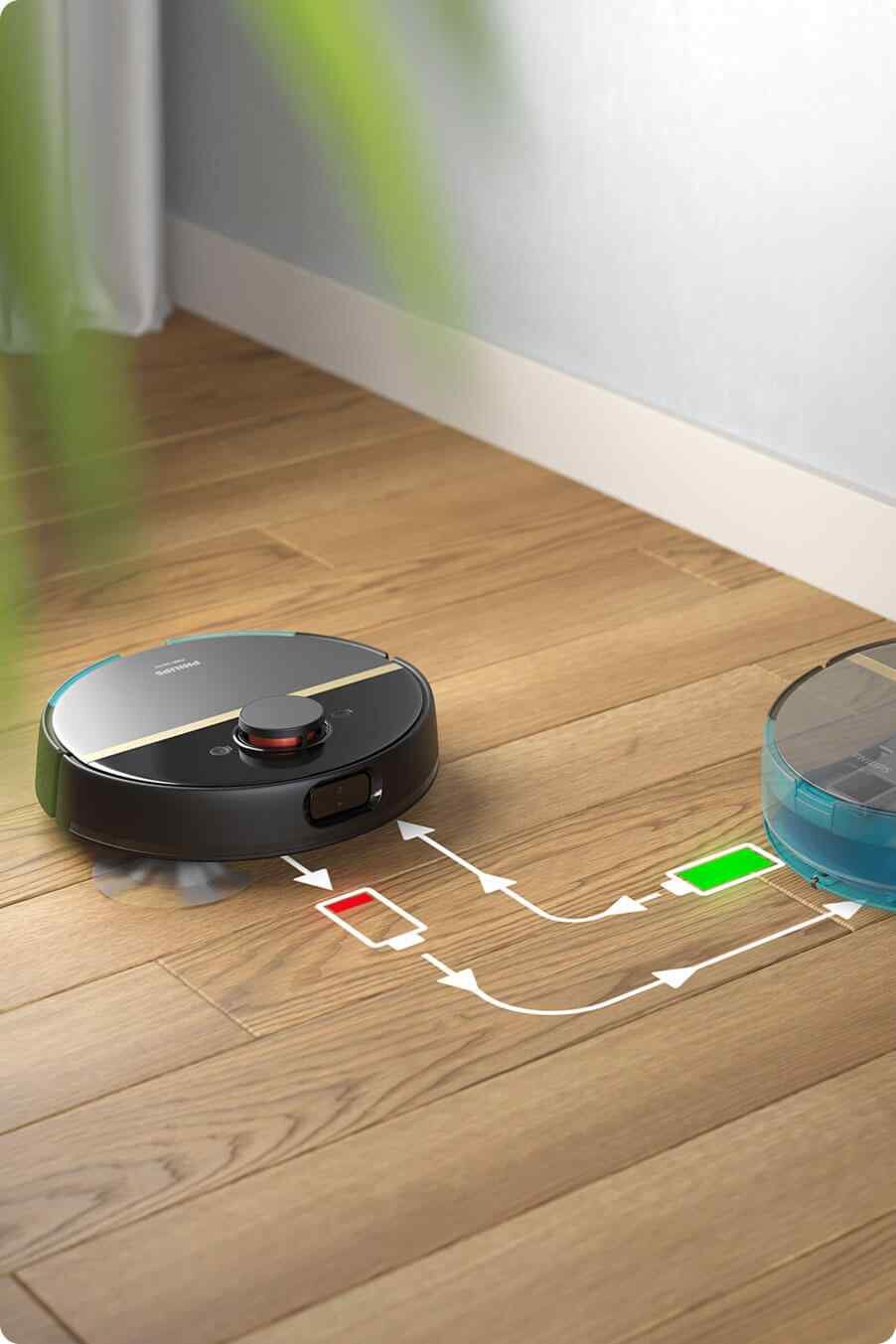 Robot sprzątający na drewnianej podłodze z widocznym logo PHILIPS. Obok robota znajduje się schemat z ikonami baterii w kolorach czerwonym i zielonym oraz strzałkami wskazującymi kierunek.