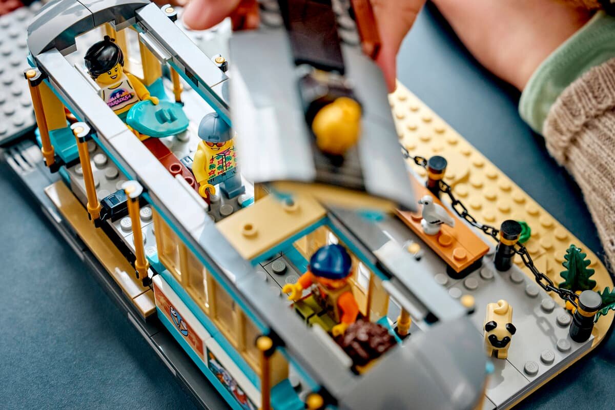 Zestaw LEGO przedstawiający tramwaj przy plaży z kilkoma figurkami w środku. Widać także fragment plaży z ławeczką i ozdobami.