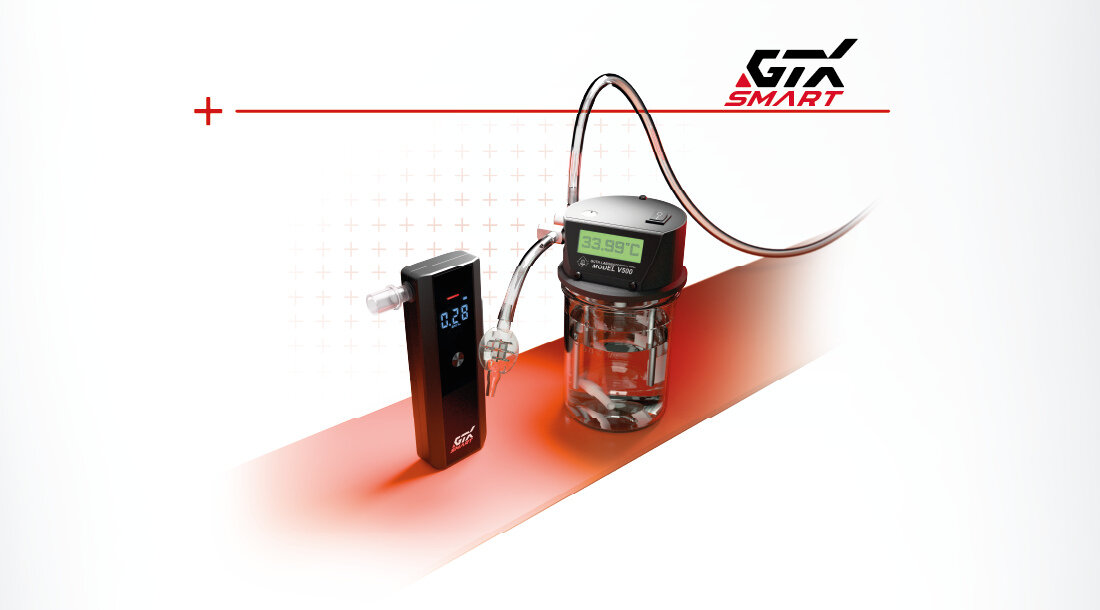 Na obrazie widoczny jest alkomat GTX Smart z wyświetlaczem pokazującym wartość 0.28 oraz urządzenie z wyświetlaczem pokazującym 33.99°C. W tle znajduje się logo GTX Smart.