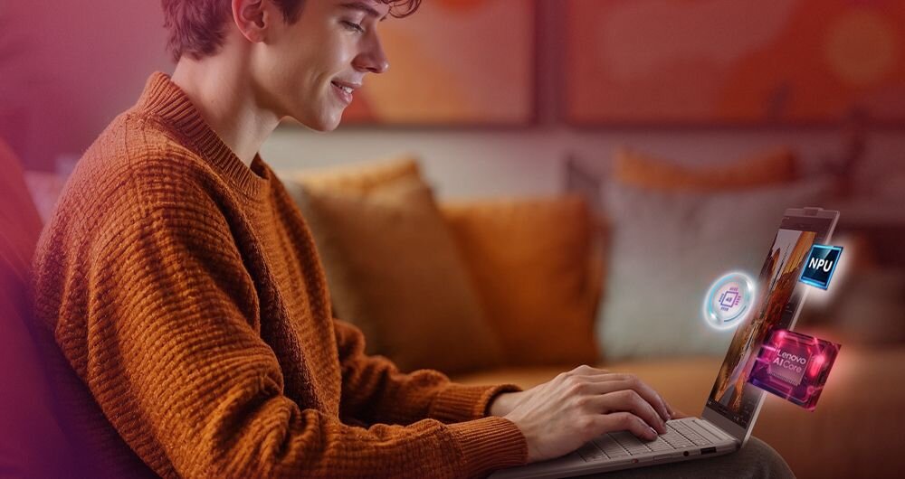 Osoba siedzi na kanapie i używa laptopa. Na ekranie laptopa widoczne są kolorowe ikony z napisami \'NPU\' i \'Lenovo AI Core\'.