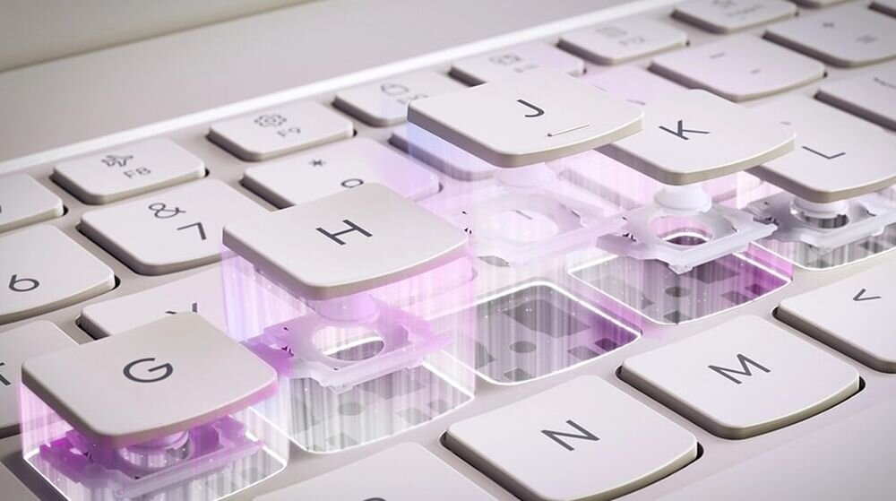 Zbliżenie na klawiaturę laptopa z unoszącymi się klawiszami G, H, J, K, ukazującymi mechanizm pod spodem. Klawisze są białe z czarnymi literami.