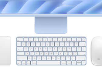 Na obrazie widoczna jest klawiatura, mysz i fragment monitora w jasnych odcieniach, z logo w kształcie nadgryzionego jabłka na myszy.
