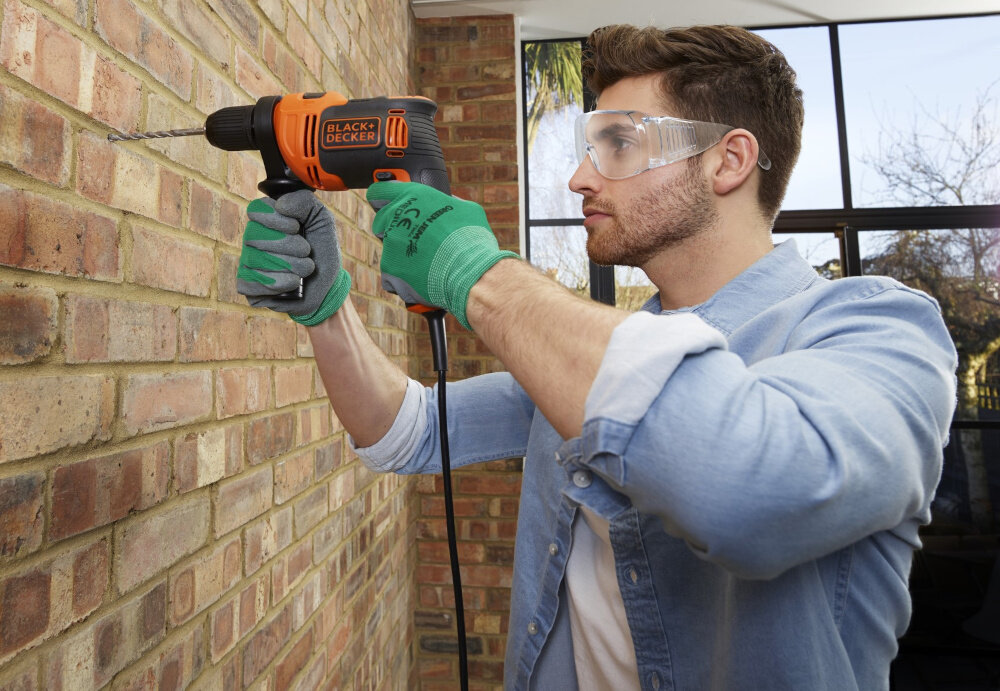 Wiertarka udarowa BLACK&DECKER BEH710-QS pomieszczenie ściana z cegły osoba wierci otwór w ścianie w tle okno moc wiercenie wydajność uniwersalność wszechstronność